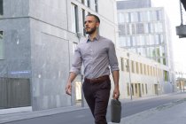 Уверенный бизнесмен гуляет по современному городу — стоковое фото