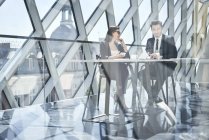 Geschäftsfrau und Geschäftsmann im Gespräch am Schreibtisch im modernen Büro — Stockfoto