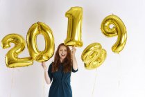 Портрет счастливой молодой женщины с золотыми воздушными шарами, датированный 2019 годом — стоковое фото