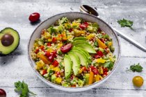 Bowl of bulgur salad with bell pepper, tomatoes, avocado, spring onion and parsley — Stock Photo