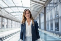 Portrait of smiling young businesswoman on moving walkway — Stock Photo