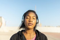 Jeune femme sportive écoutant de la musique avec écouteurs, les yeux fermés — Photo de stock