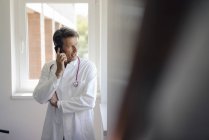 Doctor standing in hospital, using smartphone — Stock Photo