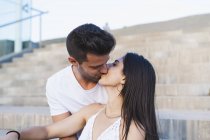 Joven pareja romántica besándose en las escaleras al aire libre - foto de stock