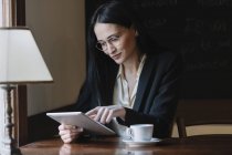 Sorridente giovane donna d'affari utilizzando tablet in un caffè — Foto stock