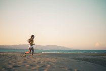 Дівчинка-підліток працює на піщаному пляжі на захід сонця — стокове фото