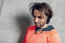 Ritratto di atleta che indossa auricolari al muro di cemento — Foto stock
