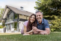 Portrait of happy couple lying in garden of their home — Stock Photo
