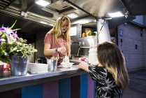 Young woman in a food truck serving customer — Stock Photo