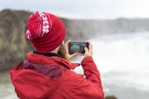 Islande, Nord de l'Islande, jeune homme photographiant une cascade — Photo de stock