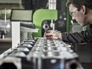 Lavoratore nella fabbrica di lavorazione dei metalli che controlla la testa del cilindro — Foto stock