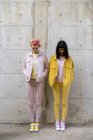 Zwei alternative Freunde amüsieren sich, tragen gelbe und rosa Jeans-Klamotten, schauen nach unten — Stockfoto