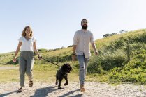 Jeune couple marchant avec chien à la campagne — Stock Photo