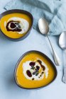 Due ciotole di zuppa di zucca fatta in casa Hokkaido guarnite con crema, olio di semi di zucca e semi di zucca — Foto stock