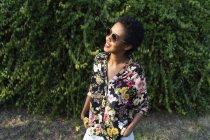 Smiling young woman wearing sunglasses and colourful blouse — Stock Photo