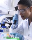 Recherche génétique, femme scientifique pipettant de l'ADN ou un échantillon chimique dans un flacon eppendorf, analyse en laboratoire — Photo de stock