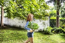 Giovane donna che trasporta erbe fresche in scatola in giardino — Foto stock