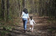 Mother and daughter running hand in hand in a park, rear view — Stock Photo