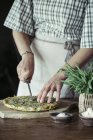 Junge Frau schneidet hausgemachte Kichererbsen und Kräuterkuchen — Stockfoto
