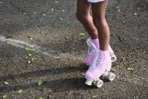 Ноги маленькой девочки в розовых роликах, катание на роликах — стоковое фото