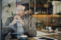 Mature businessman sitting in coffee shop, smiling — Stock Photo