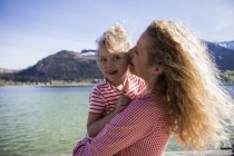 Австрія, Тіроль, Вальчзе, щаслива мати, що носить дочку біля озера. — стокове фото