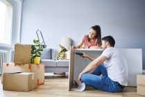 Couple dans un nouvel appartement assemblant des meubles ensemble — Photo de stock