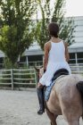 Back view of woman in dress and helmet riding on horse — Stock Photo