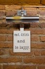 Board with a saying on brick wall in a restaurant — Stock Photo