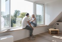 Älteres Paar sitzt mit Handy am Fenster in leerem Zimmer — Stockfoto