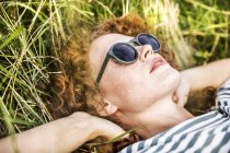 Крупним планом молодої жінки, що носять сонцезахисні окуляри, відпочиваючи на лузі — стокове фото