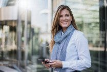 Портрет усміхненої молодої бізнес-леді зі смартфоном — стокове фото
