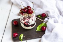 Copa de yogur natural con cerezas, mermelada de cereza y granola - foto de stock