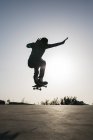 Sportlicher Mann springt mit Skateboard über Boden und zeigt Trick — Stockfoto