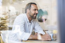 Smiling man with tablet in a cafe — Stock Photo