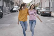 Due fidanzate allegre che si divertono in città, camminando a braccetto — Foto stock