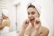 Портрет молодої жінки, використовуючи зубною ниткою у ванній кімнаті — стокове фото