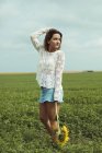 Junge Frau mit Sonnenblume in der Hand steht auf einem grünen Feld — Stockfoto