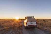 Botswana, Kalahari, zentrales Kalahari-Wildreservat, Geländewagen auf Schotterpiste bei Sonnenaufgang — Stockfoto