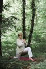 Senior woman doing yoga in the forest — Stock Photo