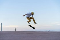 Giovane uomo che fa un trucco skateboard su una corsia al crepuscolo — Foto stock