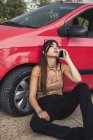 Jovem sentada à beira da estrada com uma avaria de carro chamando serviço de avaria — Fotografia de Stock