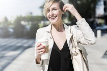Portrait of laughing businesswoman with Coffee to go walking on street — Stock Photo