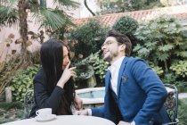 Glückliches elegantes Paar beim Gespräch in einem Gartencafé — Stockfoto