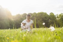 Mutter und Tochter im Sommer mit Pusteblume auf Wiese — Stockfoto