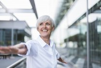 Happy senior woman in city with outstretched arms — Stock Photo