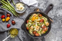 Spaghetti mit Garnelen, grünem Spargel, Tomaten, Pesto und Parmesan — Stockfoto