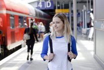 Porträt einer blonden Frau mit Rucksack am Bahnsteig — Stock Photo