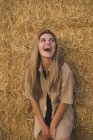 Giovane donna ridente in piedi davanti a balle di fieno, ritratto — Foto stock