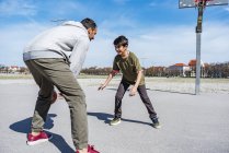 Père et fils jouant au basket sur le terrain à l'extérieur — Photo de stock